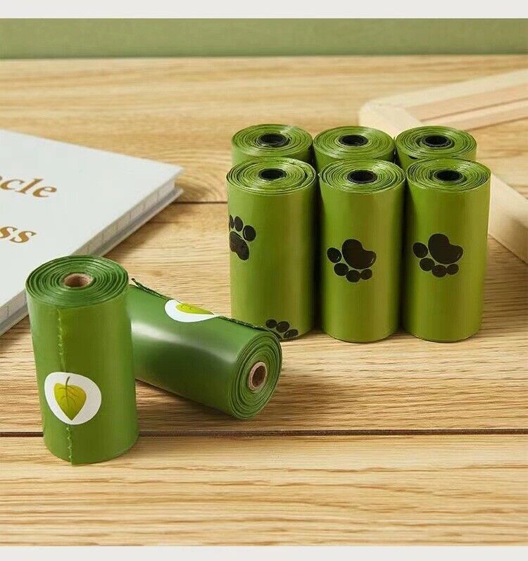 Green rolls of pet waste bags with paw prints on a wooden surface