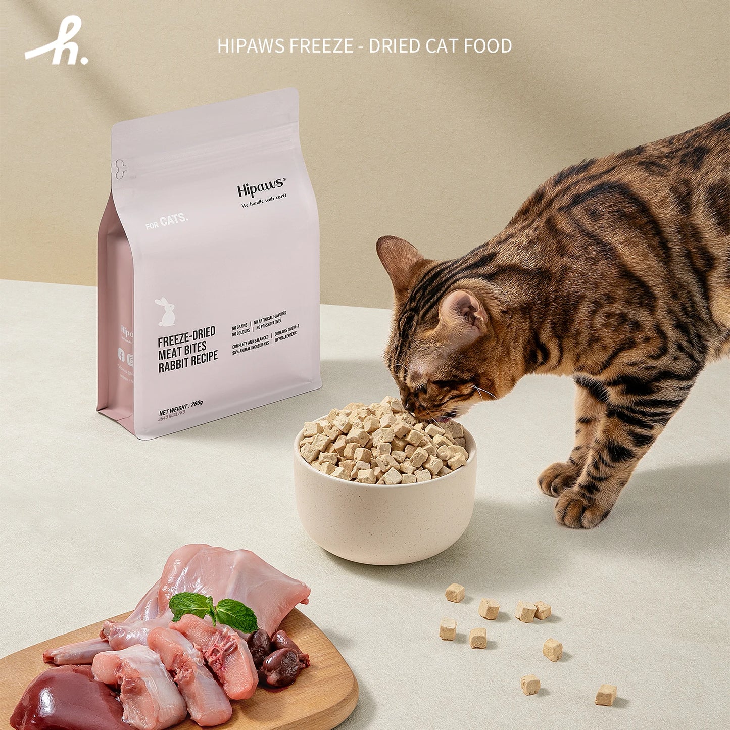 Cat eating from a bowl of freeze-dried cat food with Hipaws packaging and ingredients on a light background