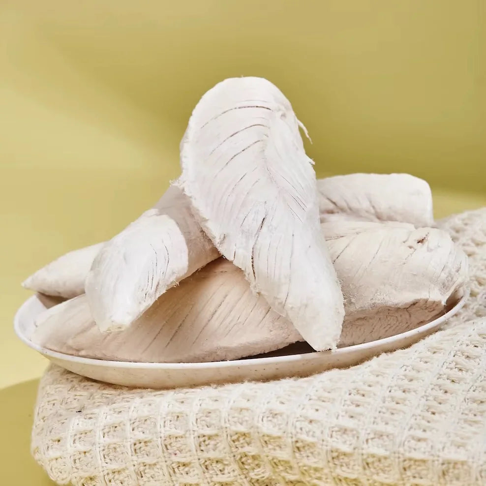 Pair of white slippers on a woven surface with a yellow background