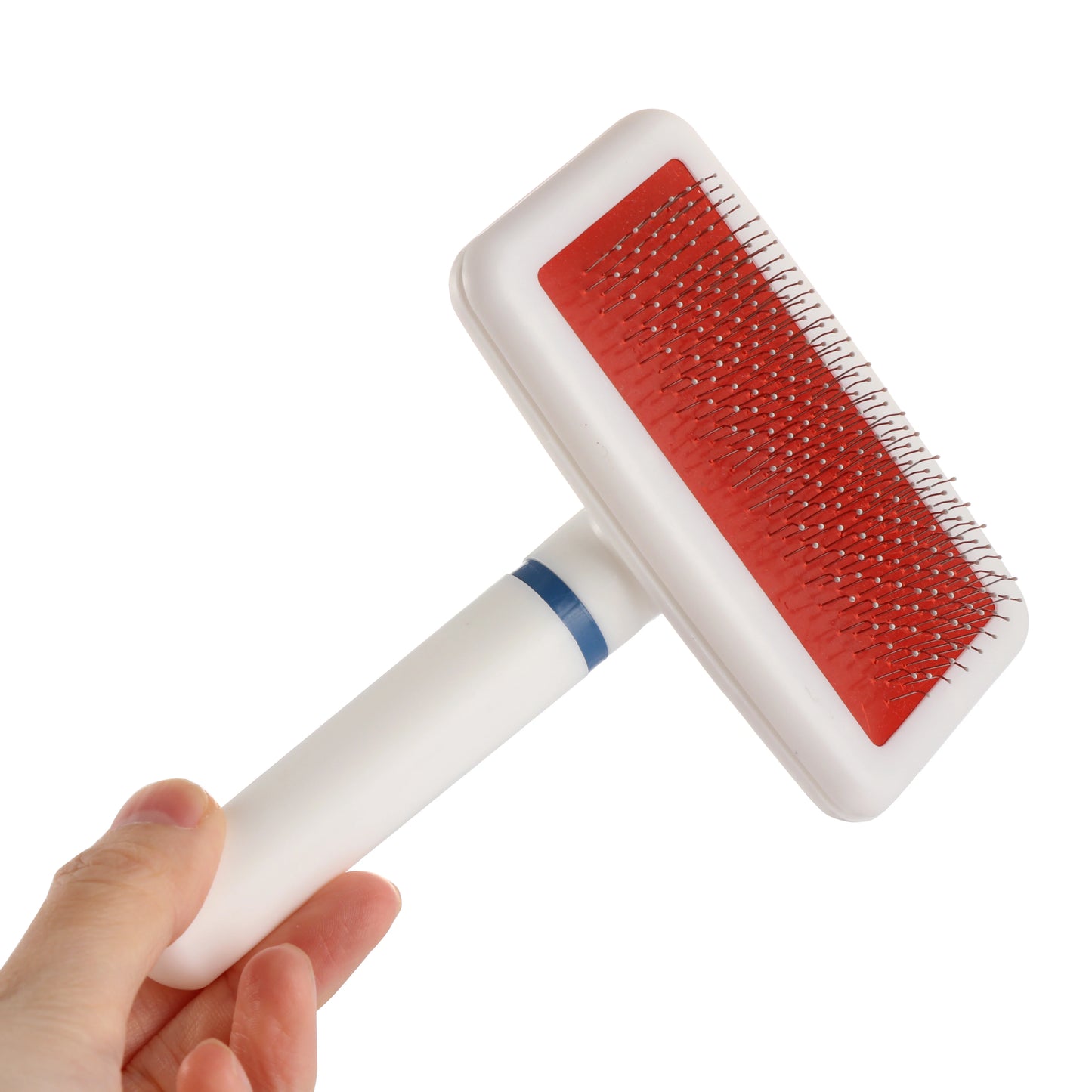 Pet grooming brush with red surface and white handle held by a hand on a white background