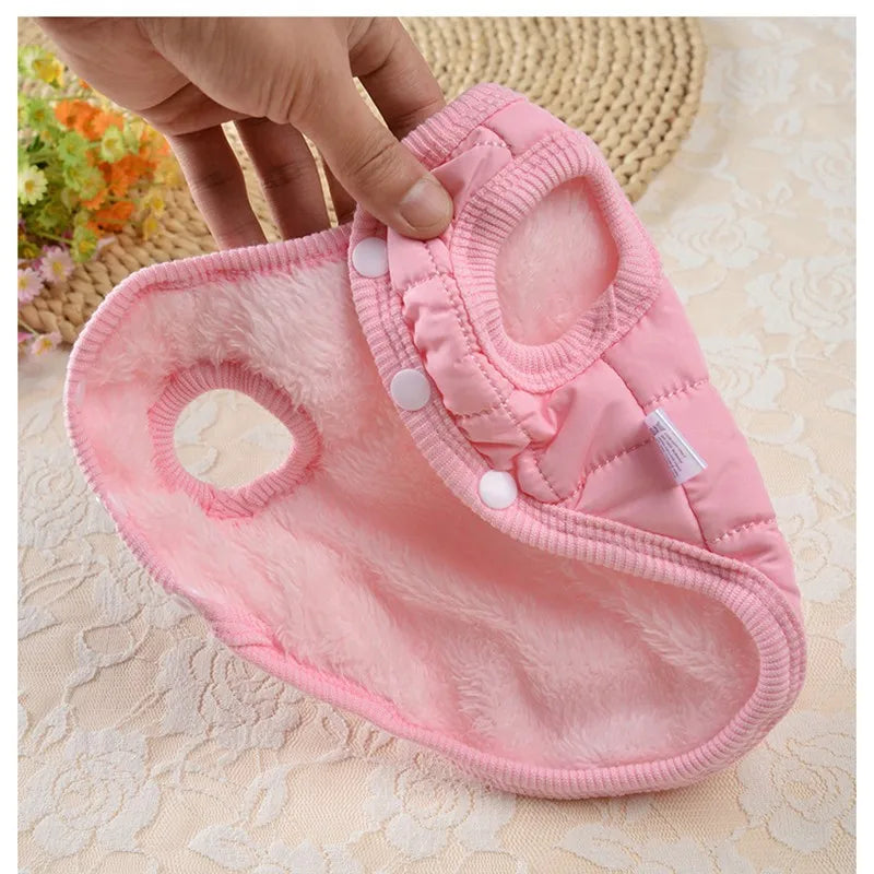 Pink baby diaper with white buttons held by a hand on a textured beige surface.