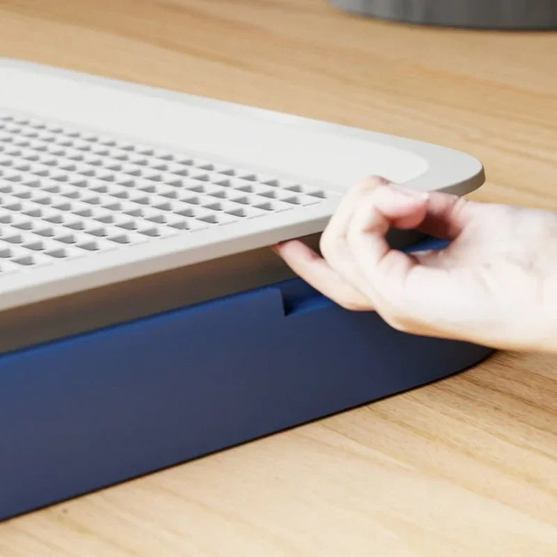 Hand interacting with a blue and gray pet carrier on a wooden surface