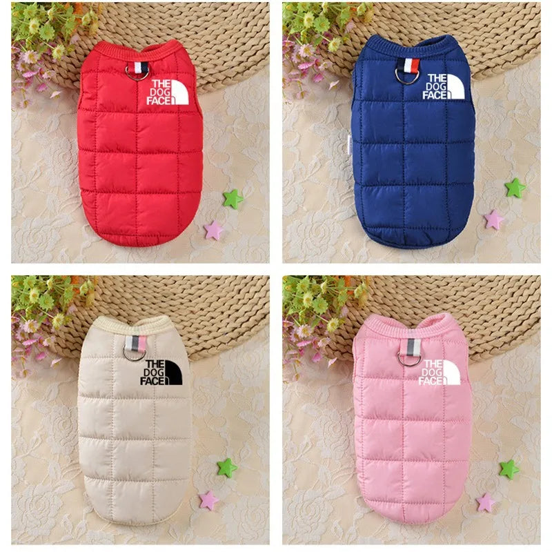 Four dog coats in red, blue, beige, and pink with 'The Dog Face' logo on a textured surface.