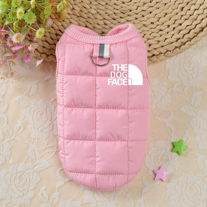 Pink dog coat with 'The Dog Face' logo on a textured surface with flowers and stars.