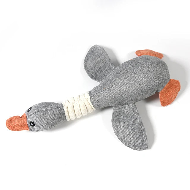 Gray plush toy with orange beak and feet on a white background