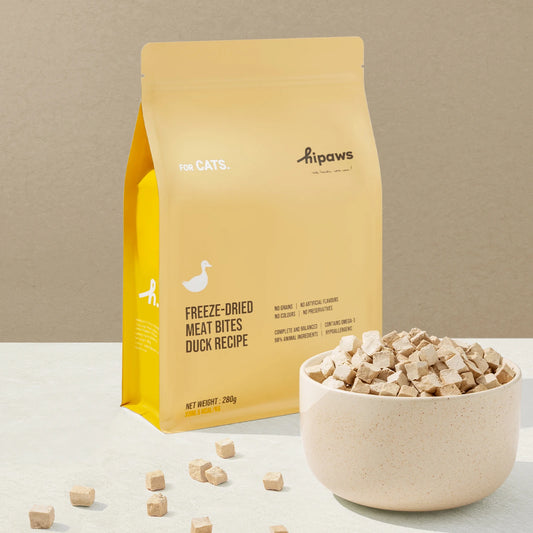 Yellow package of Hipaws freeze-dried meat bites for cats with a bowl of treats on a beige background