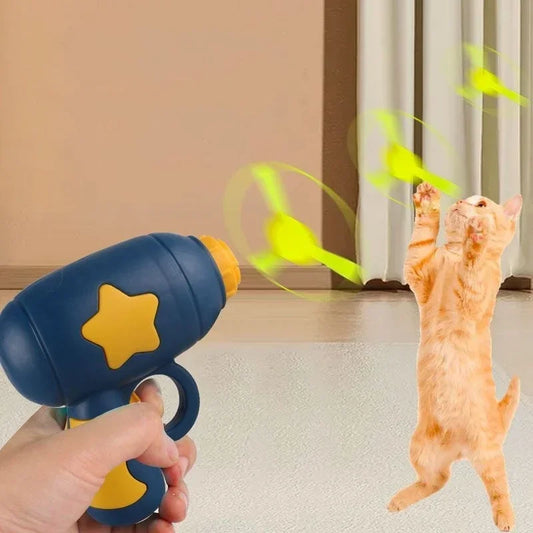 Cat playing with a toy gun and flying green birds indoors.