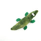 Green plush toy resembling a pickle with googly eyes on a white background