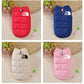 Four dog coats in red, blue, beige, and pink with 'The Dog Face' logo on a textured surface.