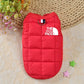 Red puffer vest for a dog with 'The Dog Face' logo on a textured surface.
