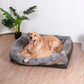 Dog lying on a gray pet bed with a plant in the background