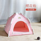 Pink pet tent with white trim on a wooden floor against a white curtain background